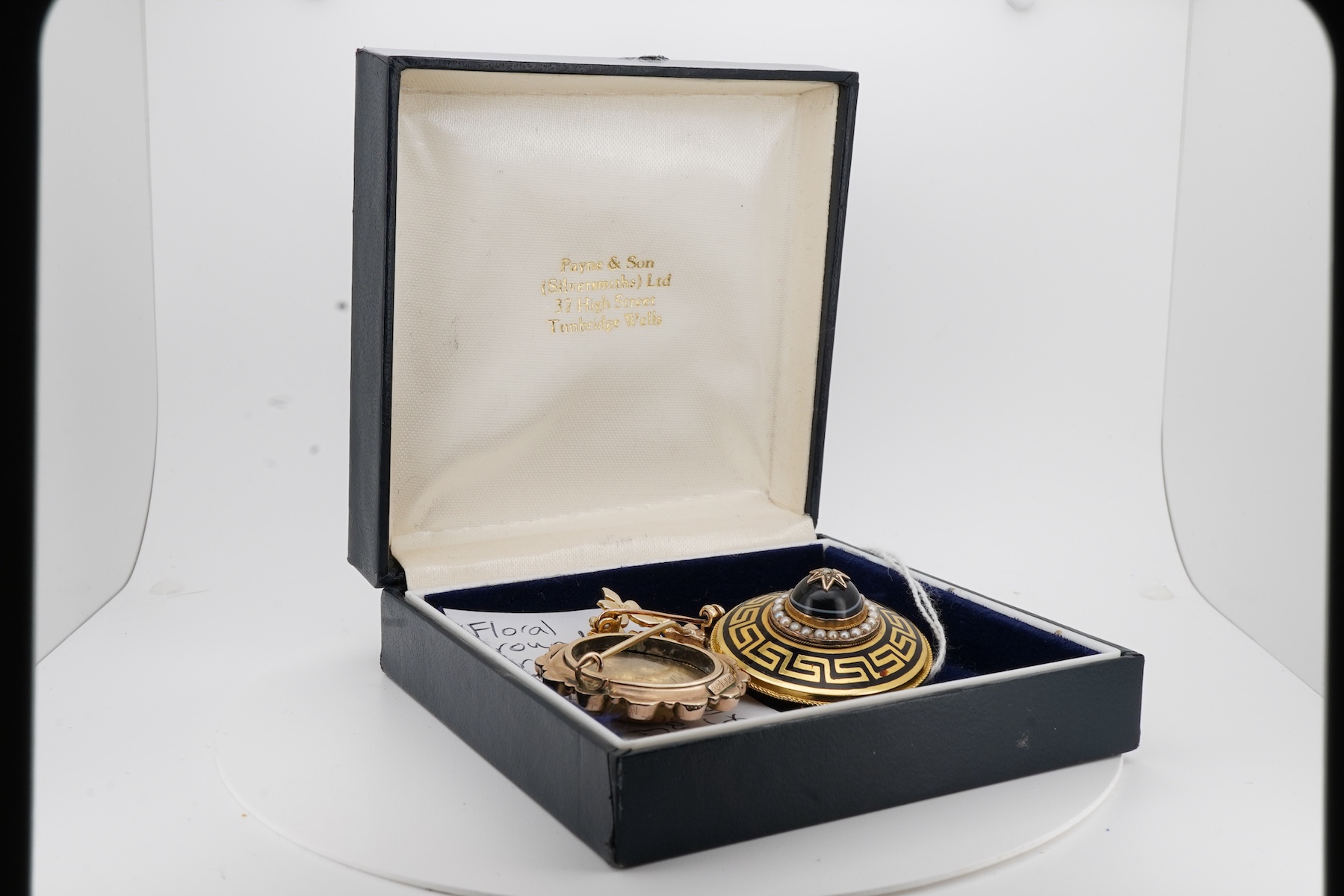 Three brooches, comprising: a Victorian circular brooch centring on a cabochon onyx set with a rose-cut diamond in a star setting, to concentring bands of seed pearls and Greek key motifs in black enamel, the reverse wit